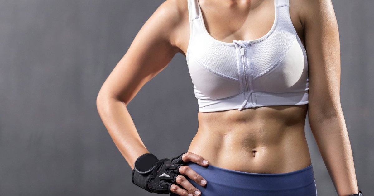 A woman wearing a white sports bra, showing her abs. [136452]